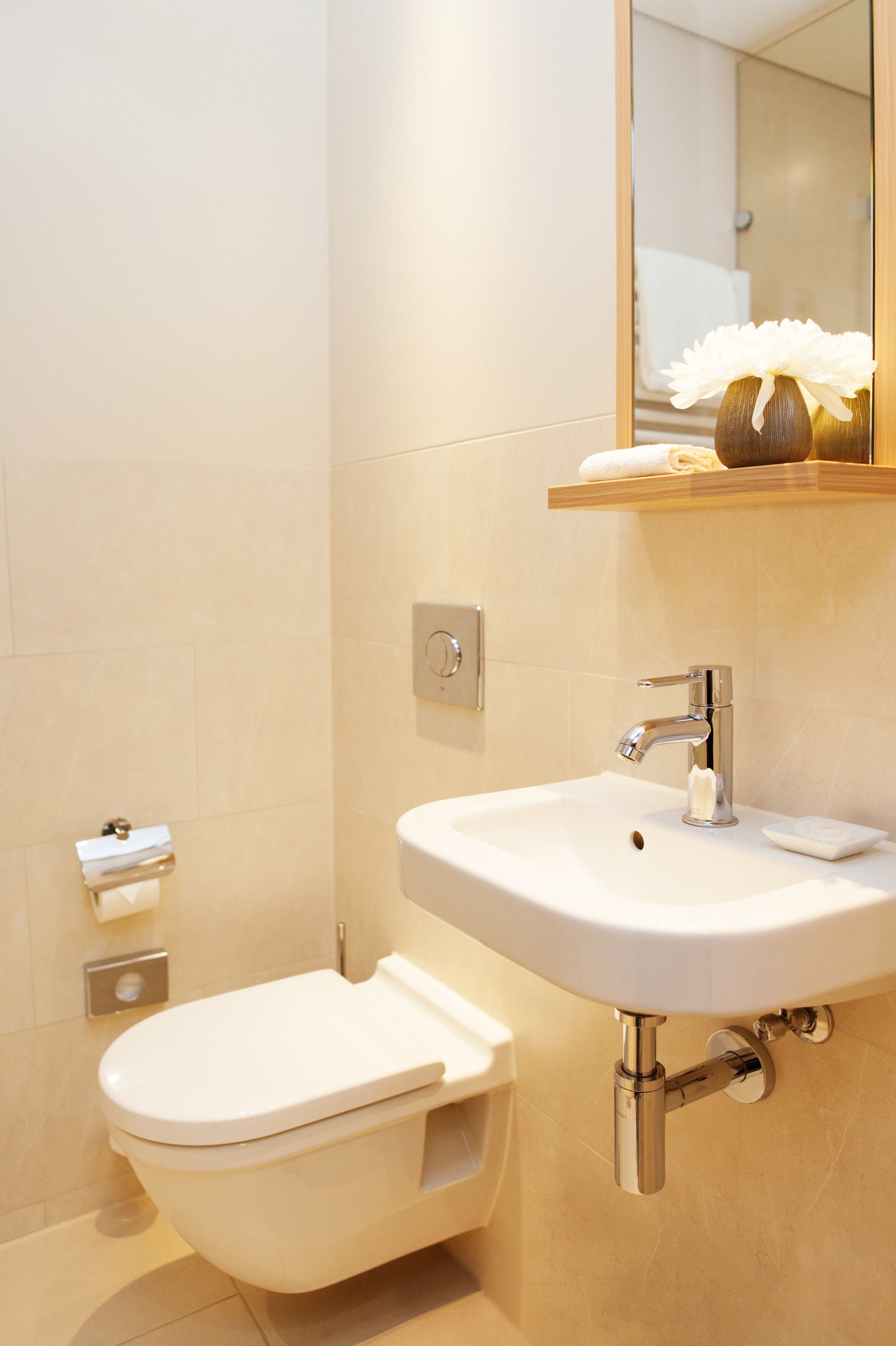 A modern bathroom with a toilet, sink, and mirror.