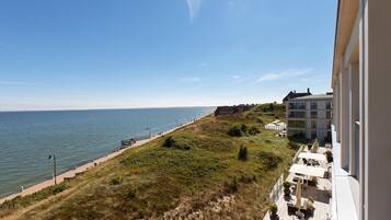 Vista costera con playa, un sendero y un edificio con terraza.