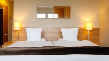 Een hotelkamer met een groot bed, twee bedlampen, een spiegel boven het bed en een houten hoofdeinde.