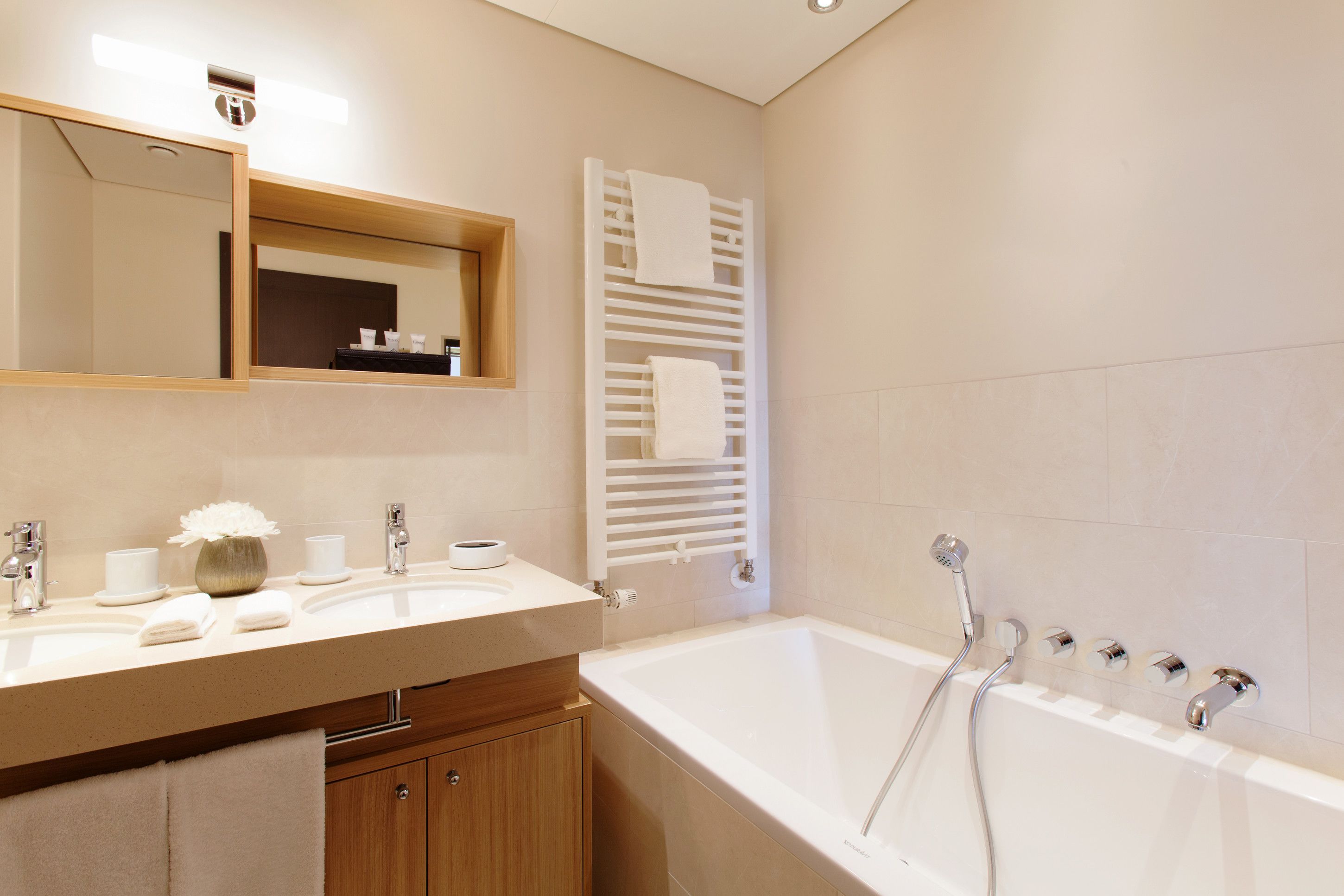 A modern bathroom with a large bathtub, a sink with a mirror above it, and a towel rack.