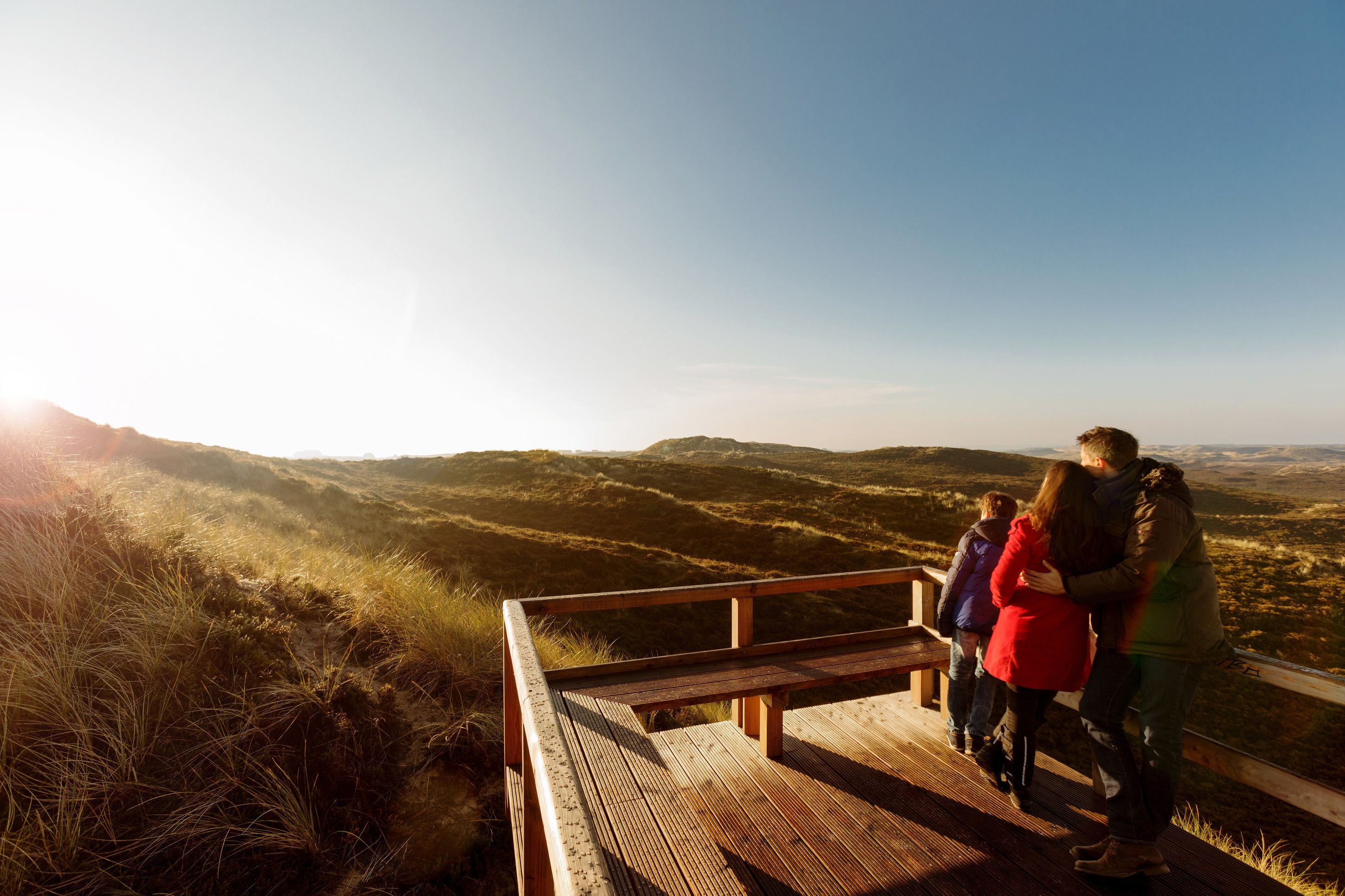 A wooden viewing platform overlooking a hilly landscape.