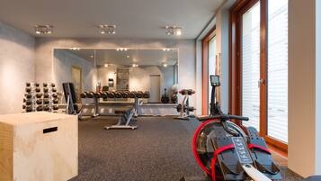 Uma academia com equipamentos de exercício, um espelho e uma janela grande.
