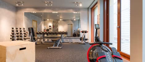 Un gimnasio con equipo de ejercicio, un espejo grande y un ventanal.
