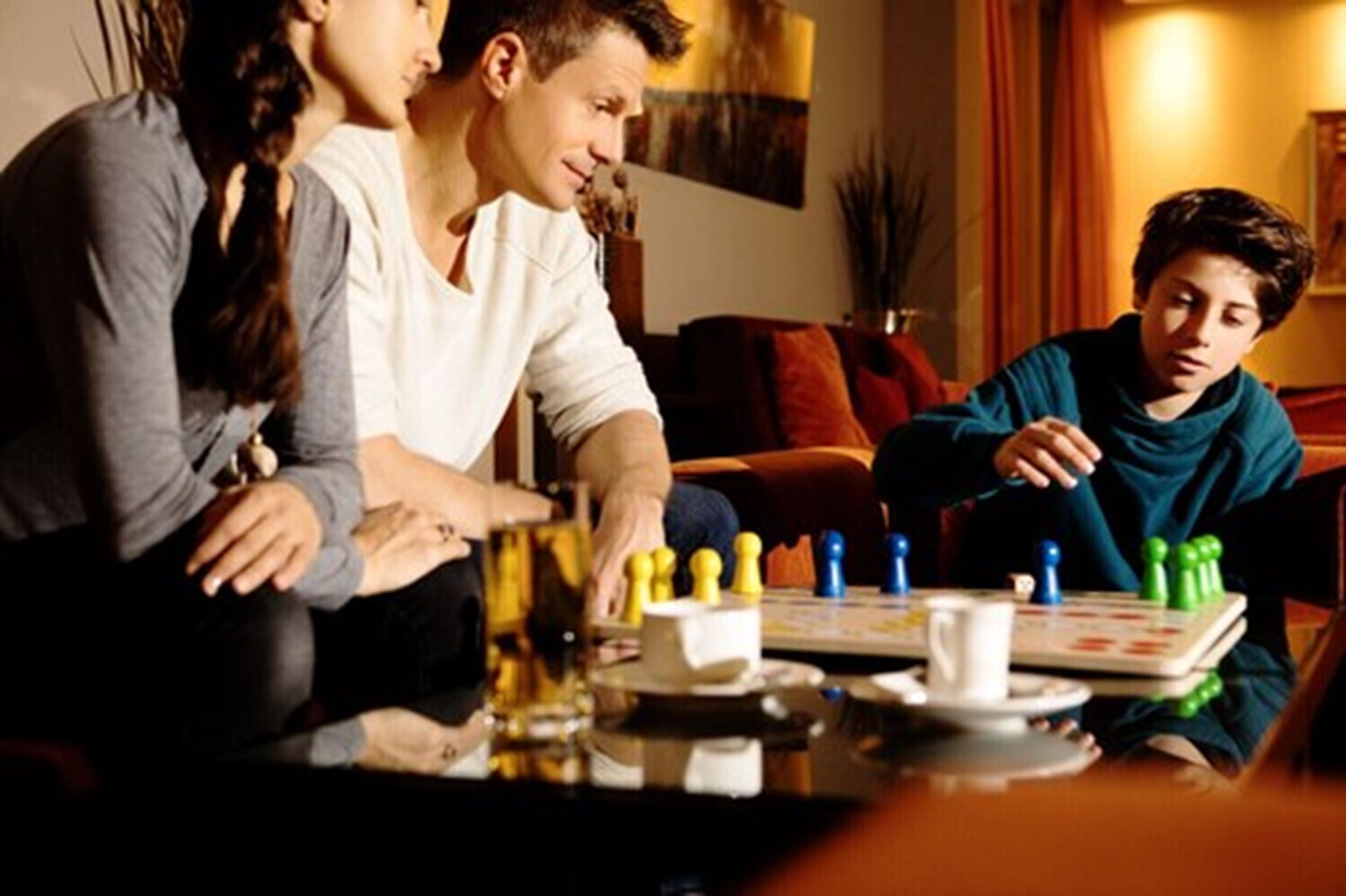 Un groupe de personnes jouant à un jeu de société autour d’une table dans une pièce à l’éclairage chaleureux.