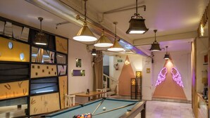 Une table de billard avec un panneau néon en forme d’aile en arrière-plan.