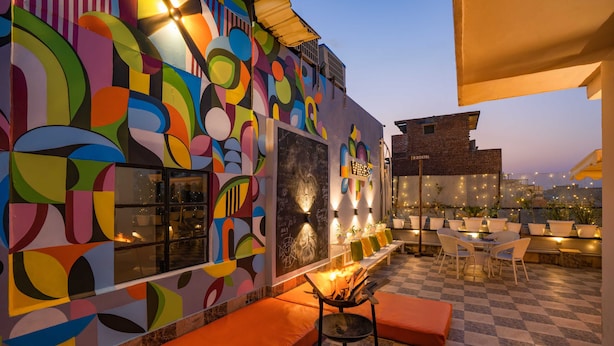 Un bar situé sur un toit, agrémenté d’œuvres d’art murales abstraites et colorées, de sièges en plein air et d’un foyer.