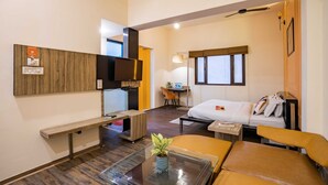 Une chambre d’hôtel de taille réduite, comprenant un lit, un bureau, une chaise et une petite table agrémentée d’une plante.