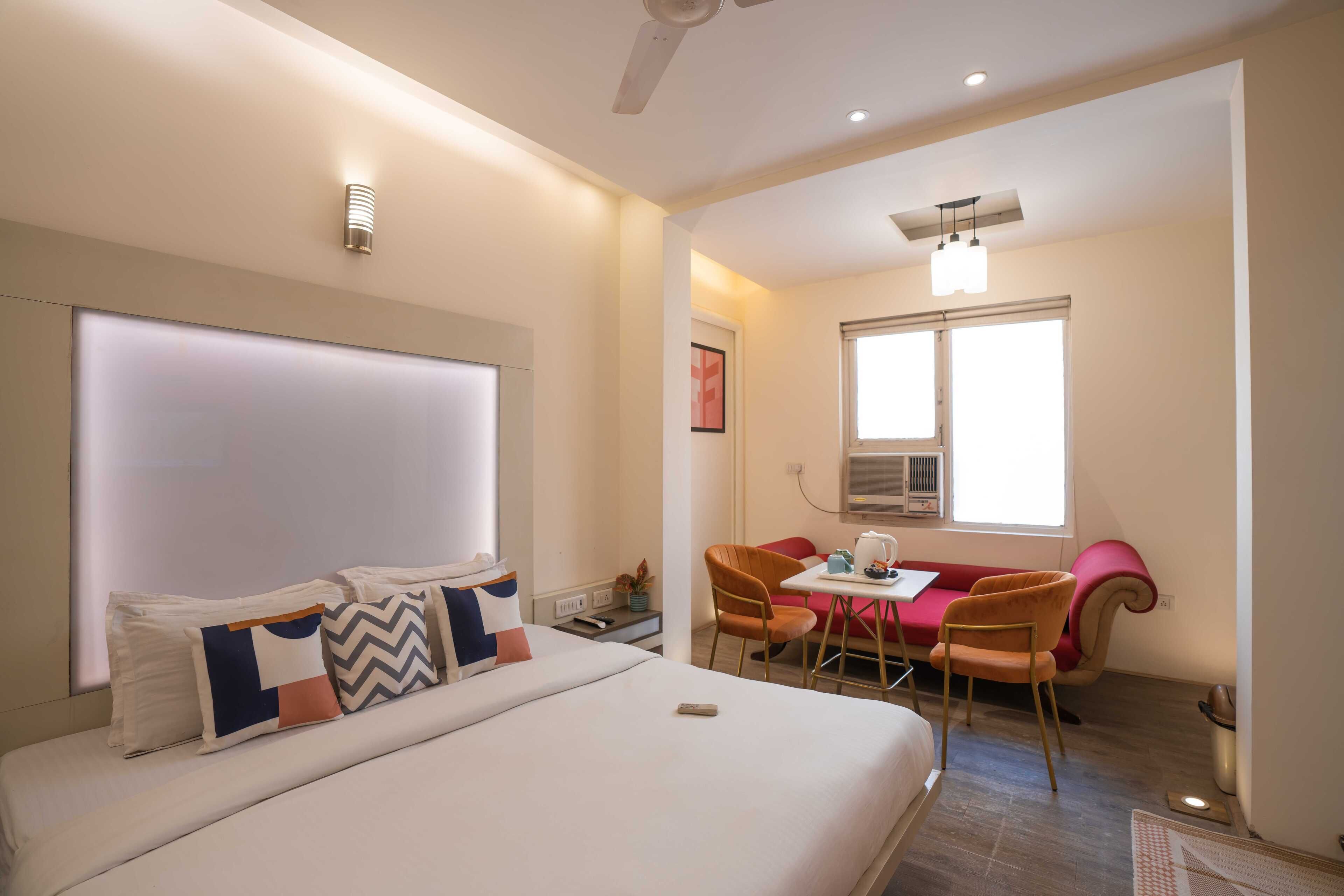 A modern hotel room with a large bed, a desk with a chair, and a window providing natural light.