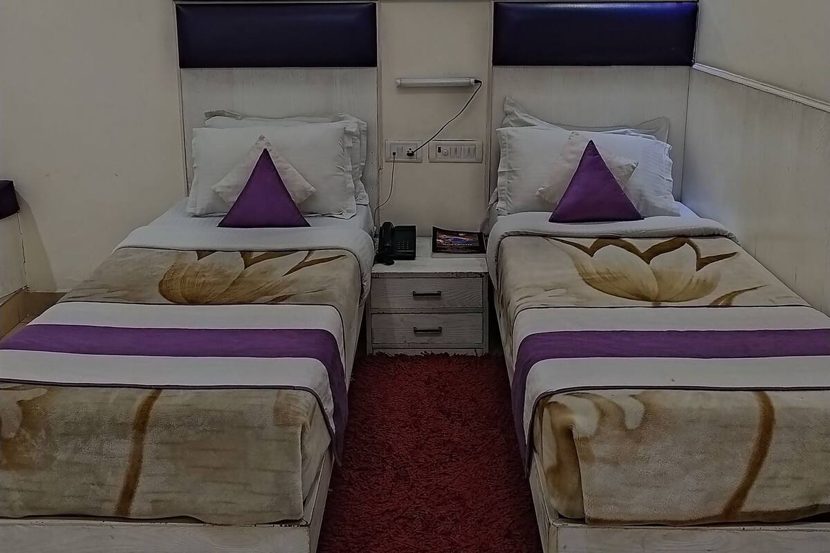 A twin room with two beds, each with a pillow and a phone on a bedside table.