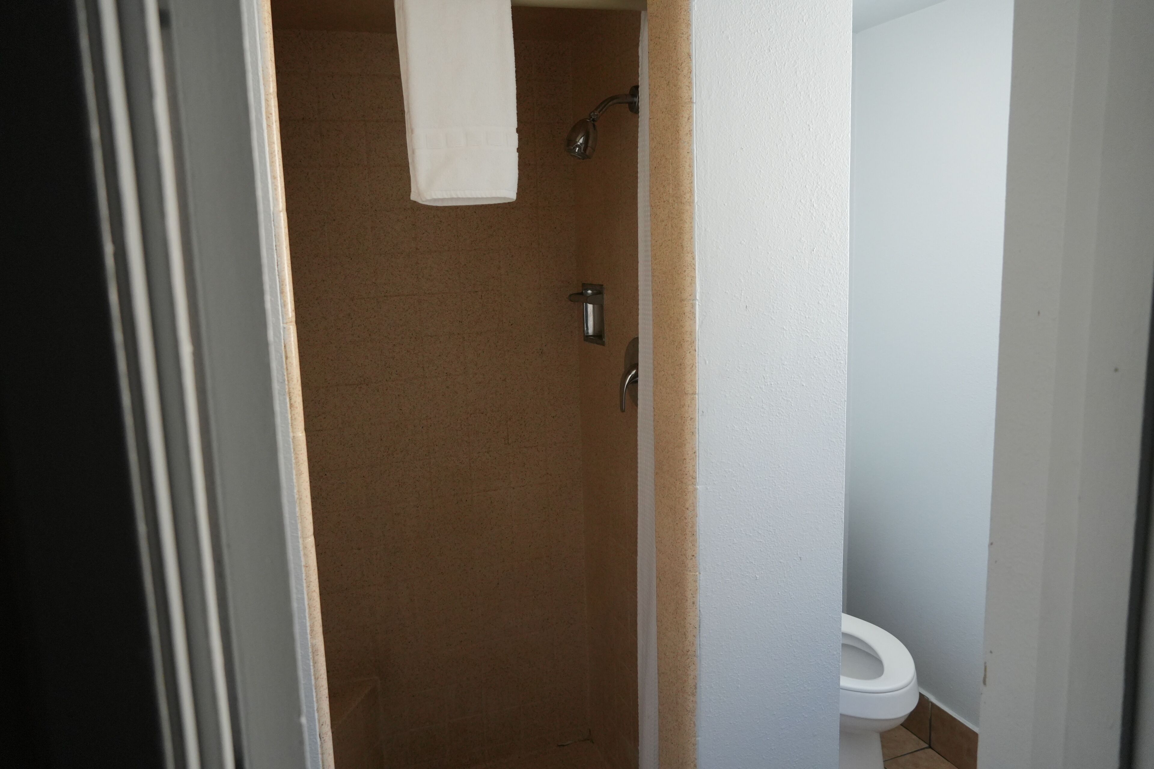 A bathroom with a shower, toilet, and a towel hanging on the wall.