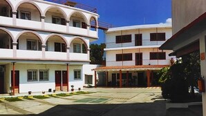 A courtyard with a multi-story building featuring balconies and a covered area. - Hotel Hacienda de Zapata (Jiutepec)