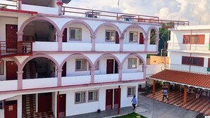 A multi-story building with a central courtyard, featuring balconies and a covered area with a checkered floor. - Hotel Hacienda de Zapata (Jiutepec)
