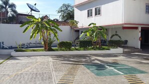 A building with a white exterior, a satellite dish, and a parking area with directional arrows. - Hotel Hacienda de Zapata (Jiutepec)