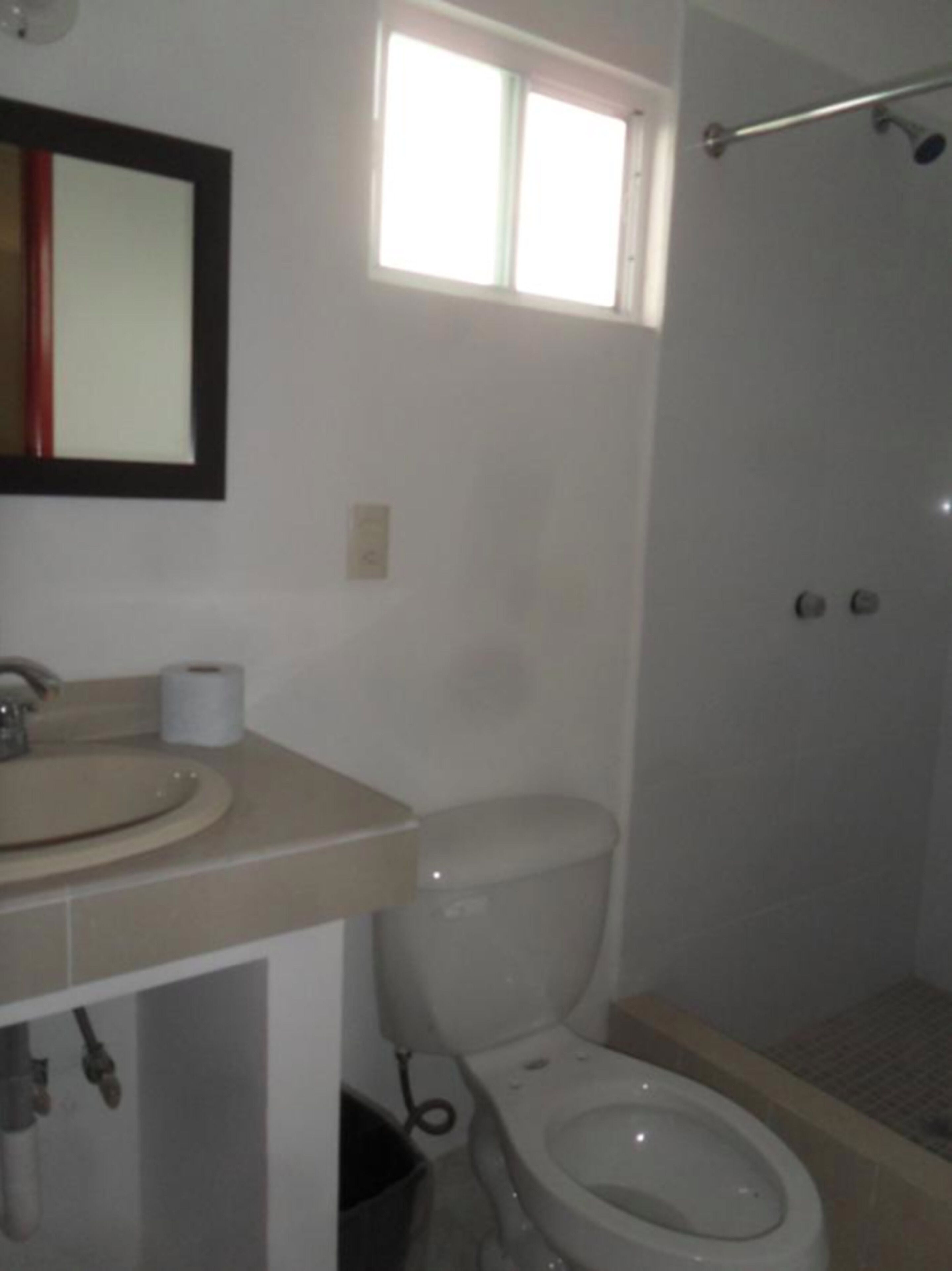 Un baño con inodoro, lavamanos y ventana.