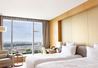 A hotel room with two beds, a view of the city, a desk, and a chair.