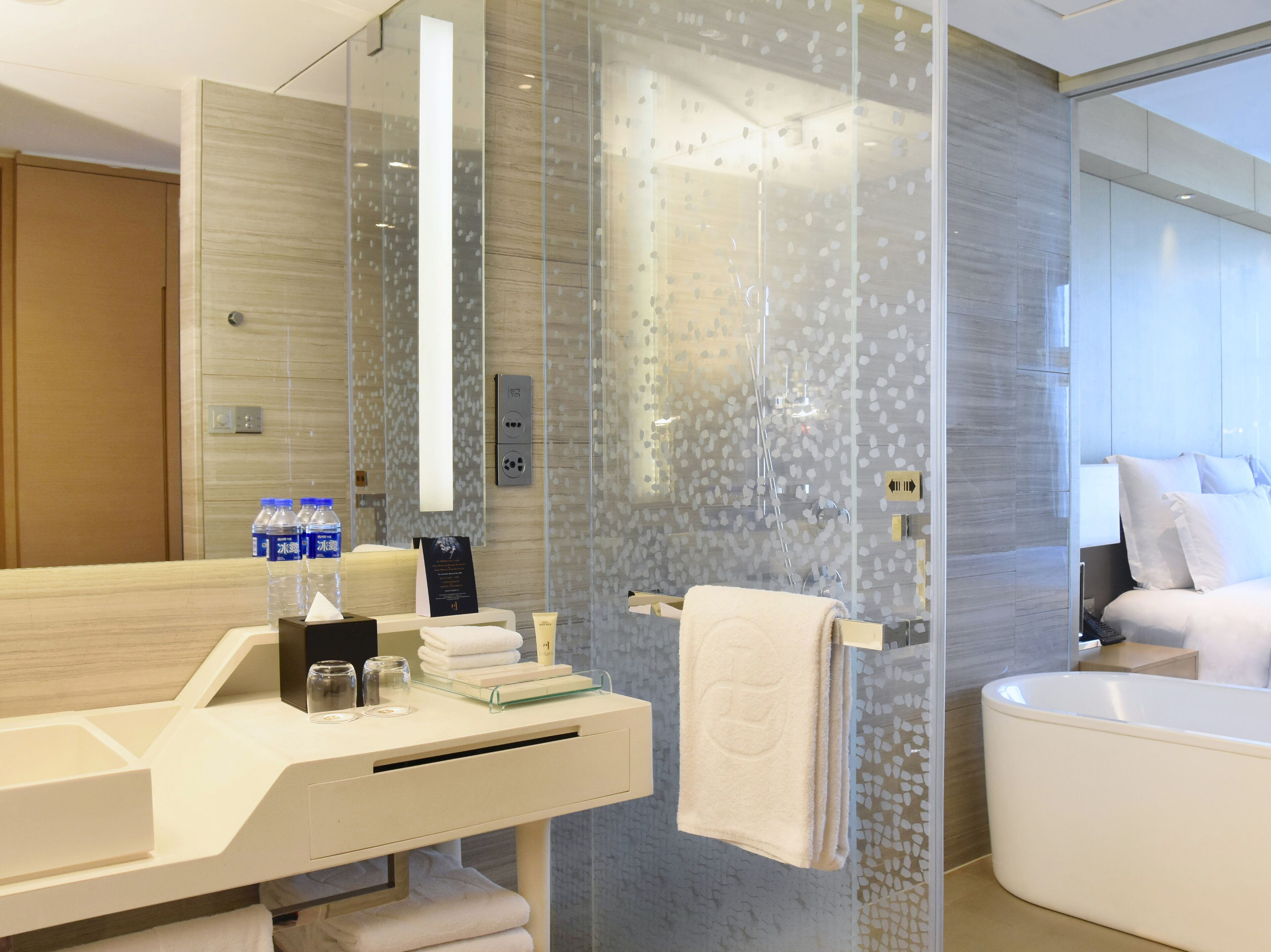 A modern bathroom with a glass shower enclosure, a white bathtub, and a vanity with toiletries.
