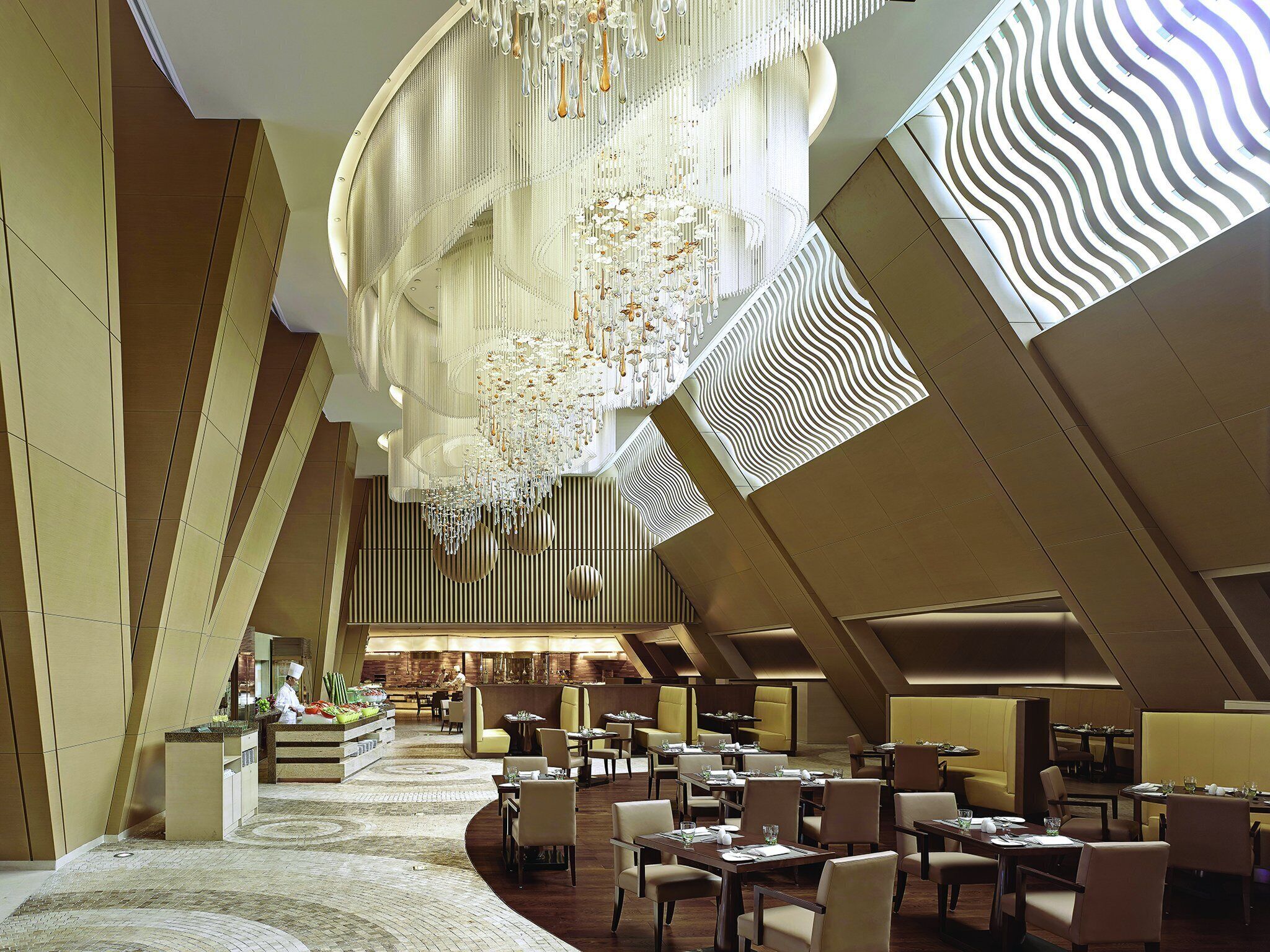Un restaurant moderne doté d’un haut plafond, de luminaires originaux et d’un bar central.