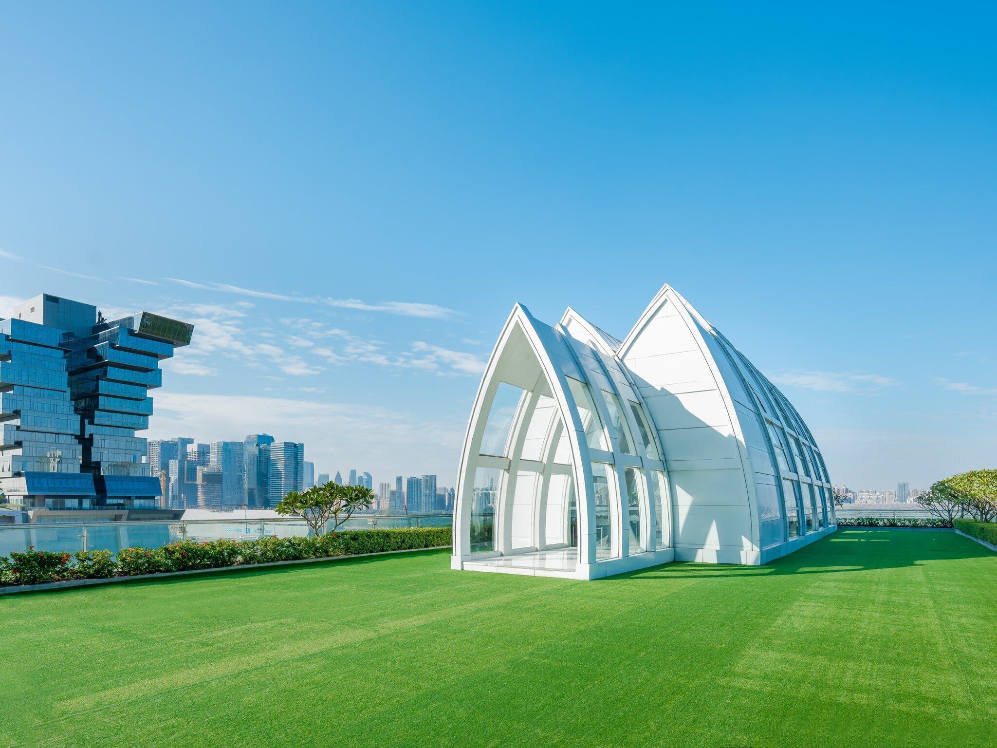 A modern building with a unique architectural design, featuring a glass facade and a green lawn in front.