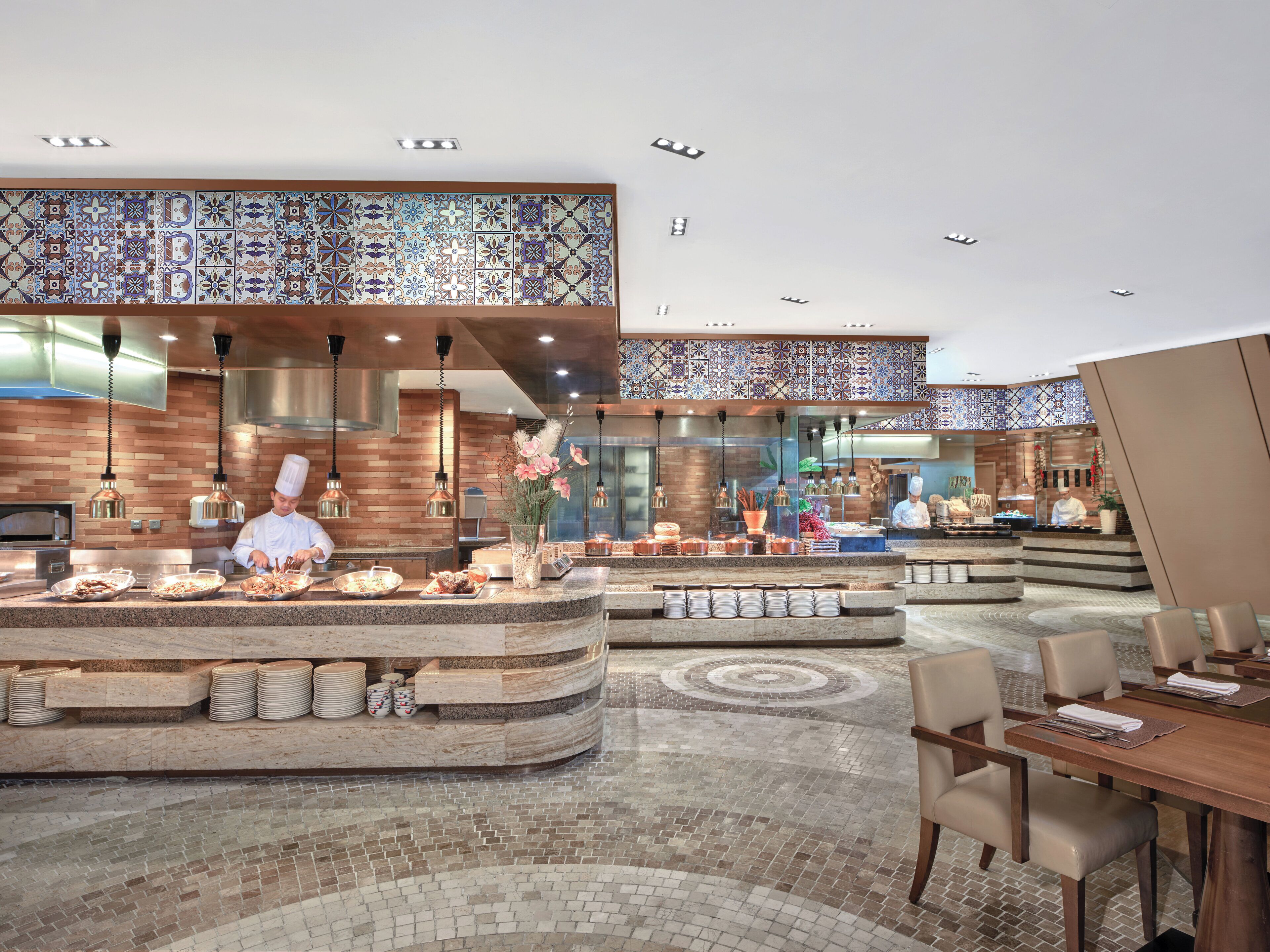 A modern restaurant with a central island, multiple seating areas, and a decorative ceiling.