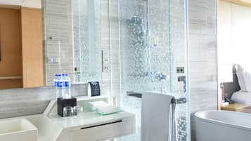 Un baño moderno con cabina de ducha de vidrio, un lavabo blanco con artículos de aseo y una bañera.