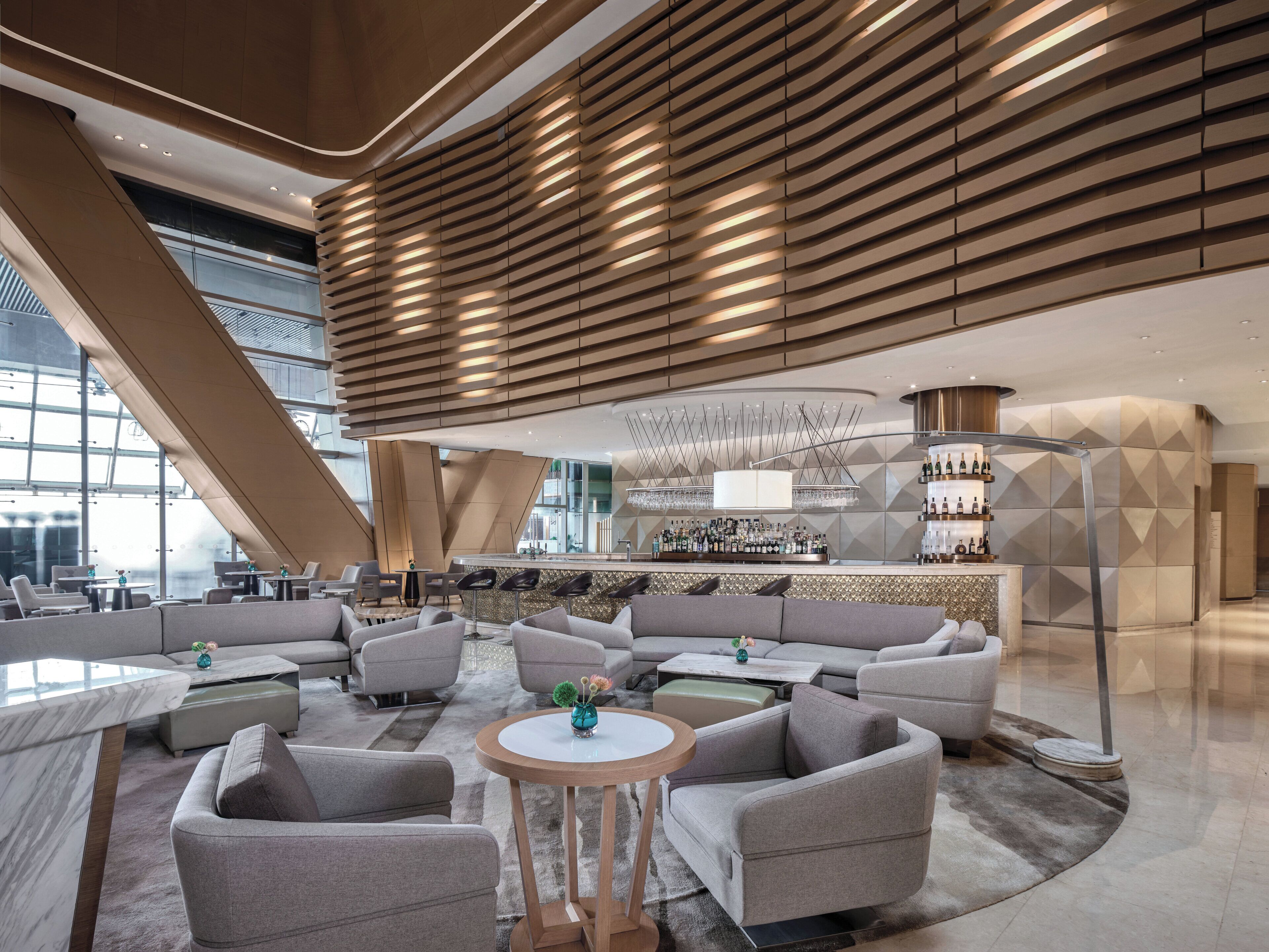 A modern lobby with a bar area, seating arrangements, and a large window providing natural light.