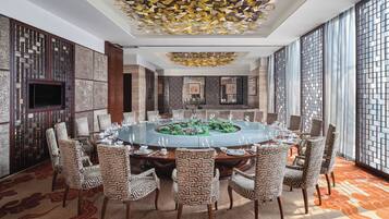 A conference room with a round table, patterned chairs, and a decorative ceiling.