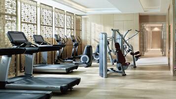 A modern gym with treadmills, elliptical machines, and weight equipment.