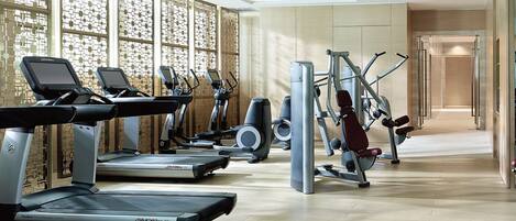 A modern gym with treadmills, elliptical machines, and weight equipment.