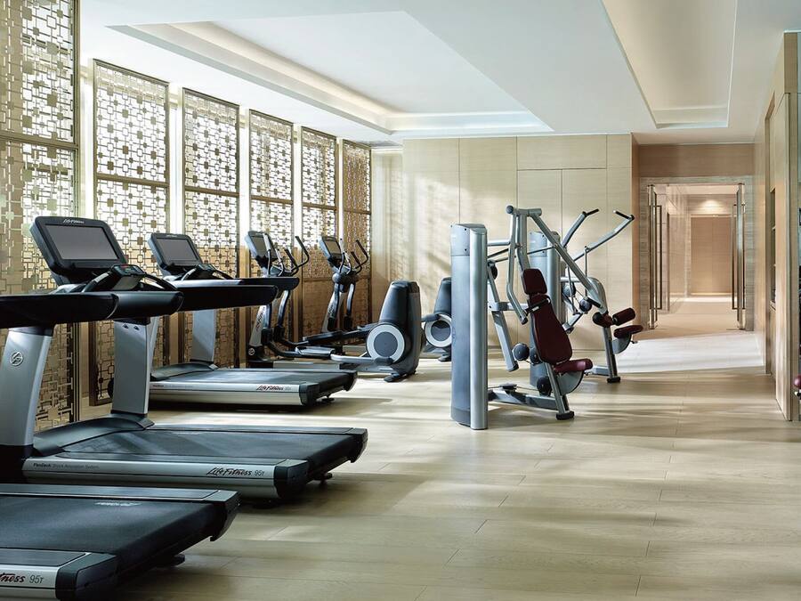 A modern gym with treadmills, elliptical machines, and weight equipment.