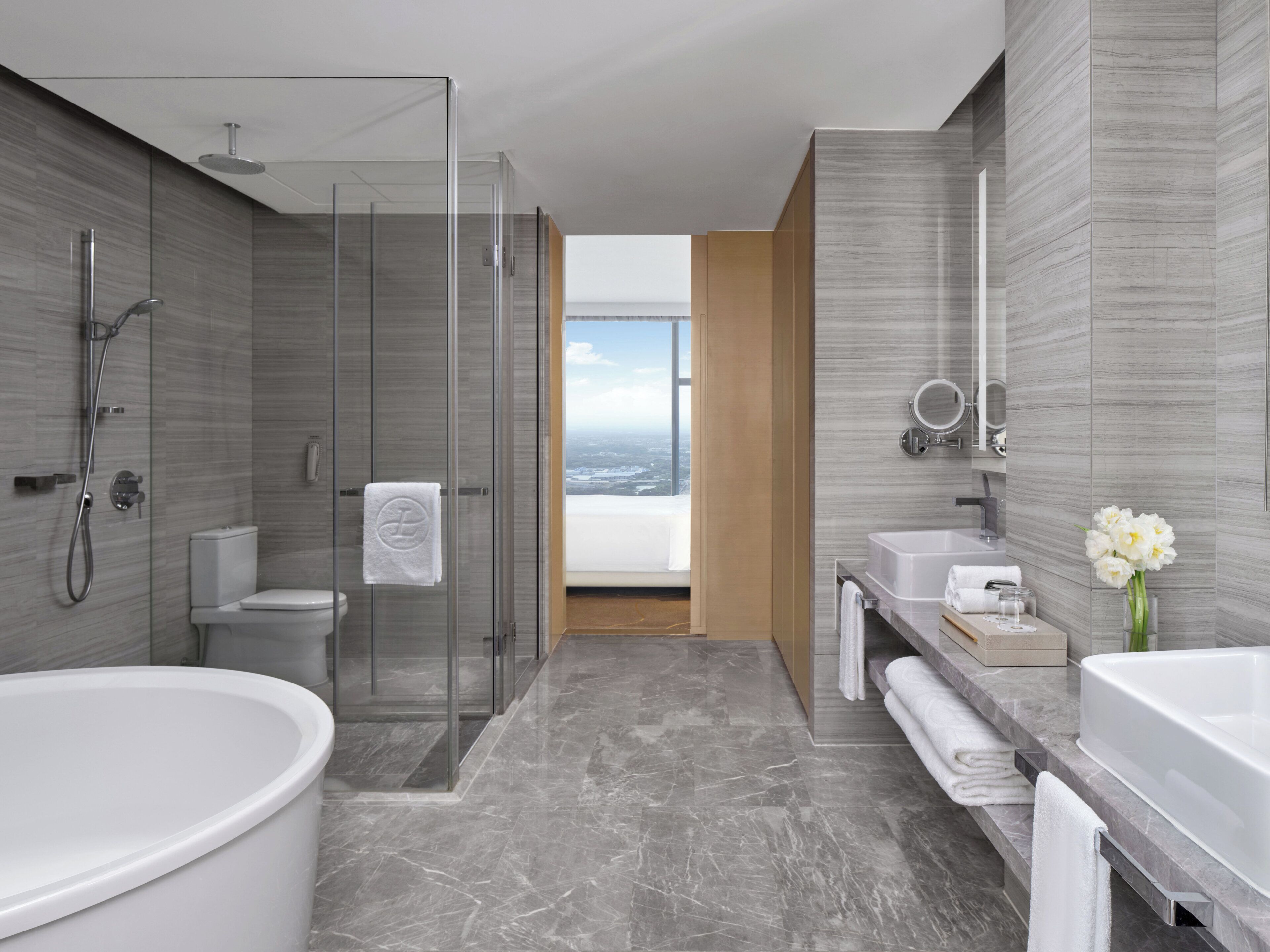 Un baño moderno con ducha envuelta en vidrio, una bañera grande y un lavamanos con espejo.