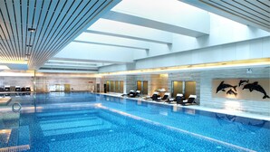 Una gran piscina cubierta con numerosas tumbonas y suelo de baldosas.