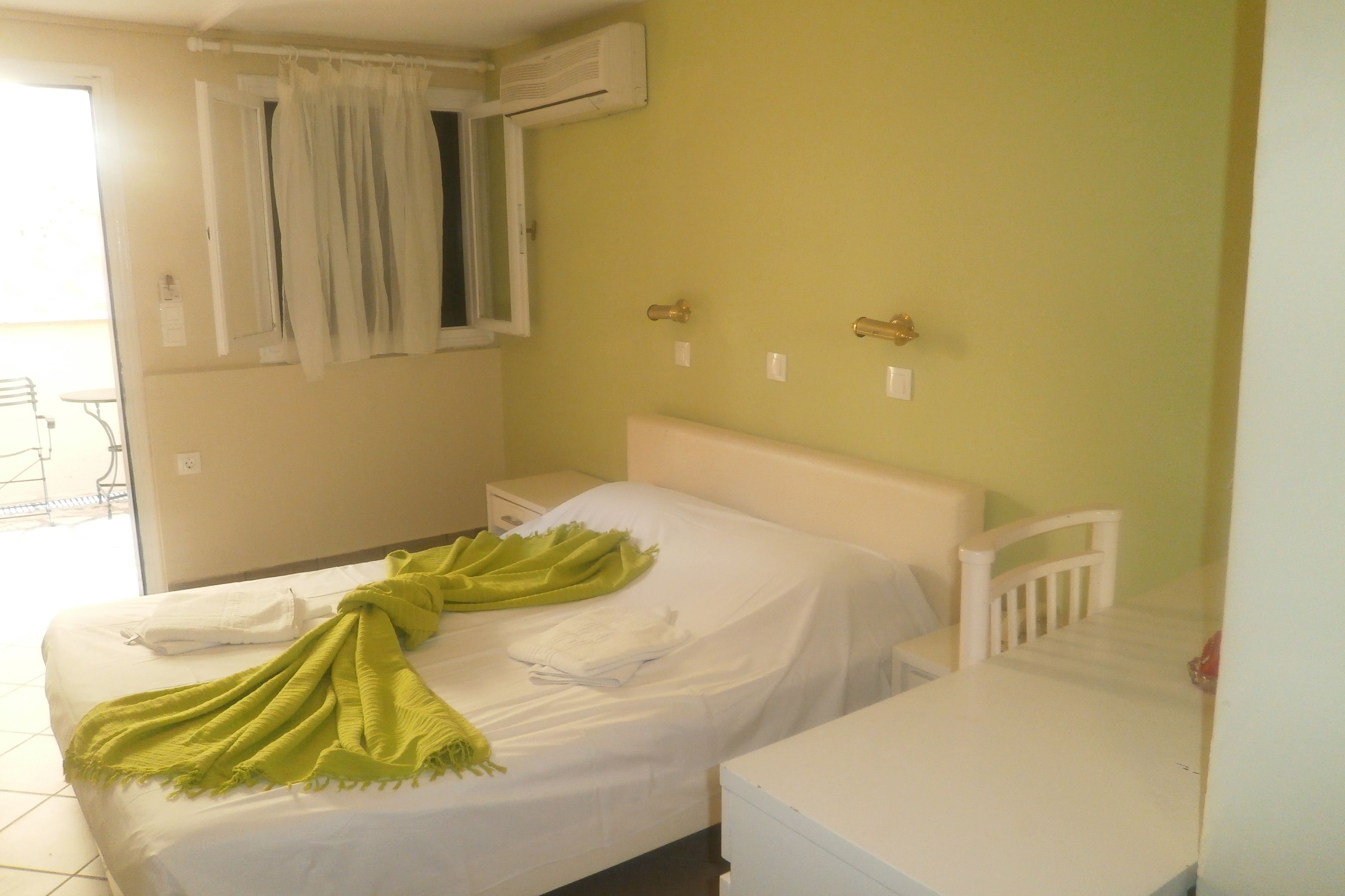 Ein Zimmer mit zwei Betten, einem weißen Tisch und einem Fenster mit Vorhängen.