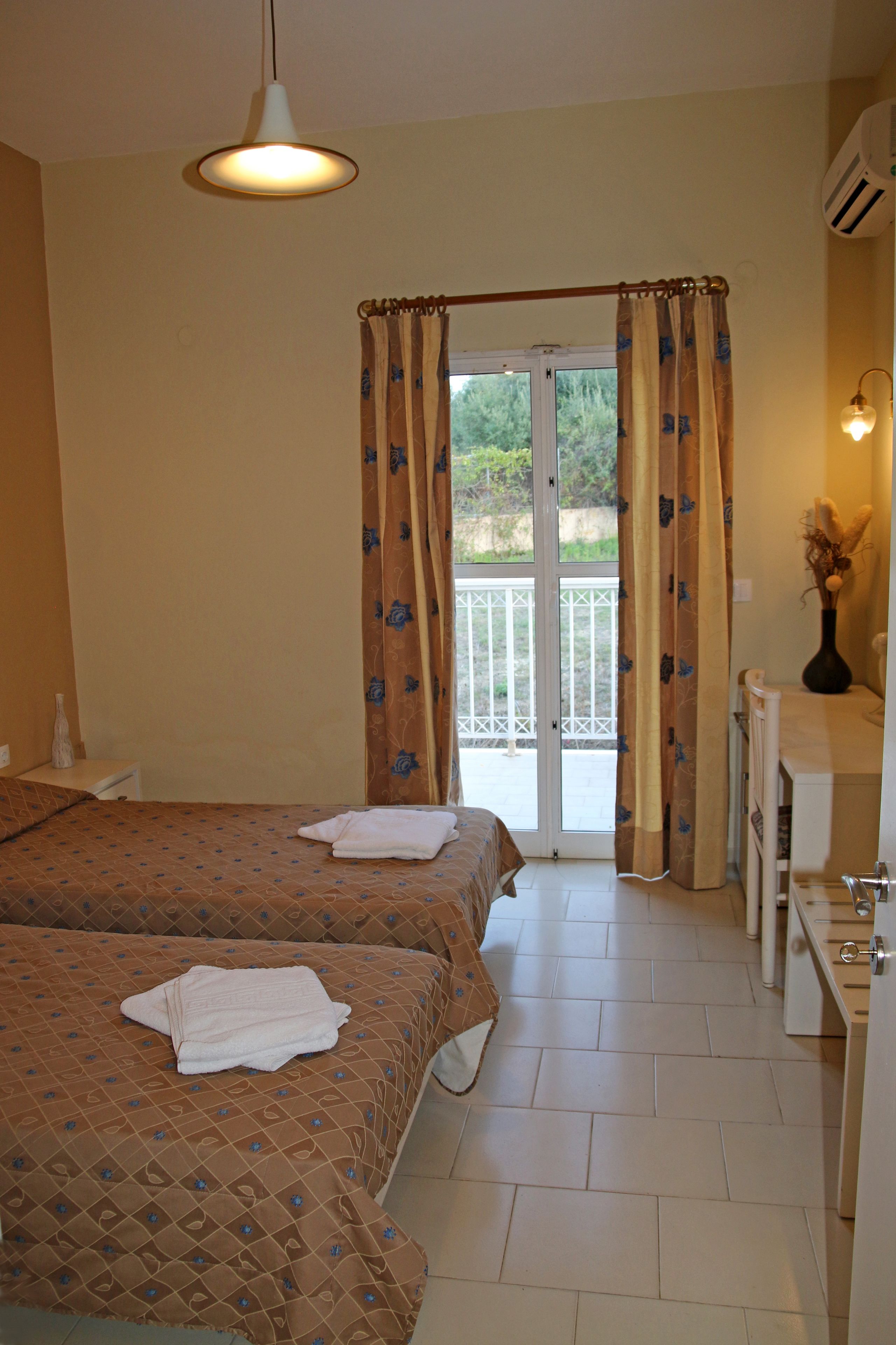 Ein Hotelzimmer mit zwei Betten, einem Balkon und einem Badezimmer.