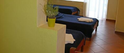 A room with two beds, a dining table, and a potted plant.