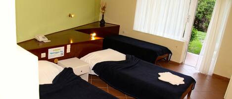 Habitación de hotel con dos camas, un escritorio con teléfono, un florero con flores y una ventana con cortinas.