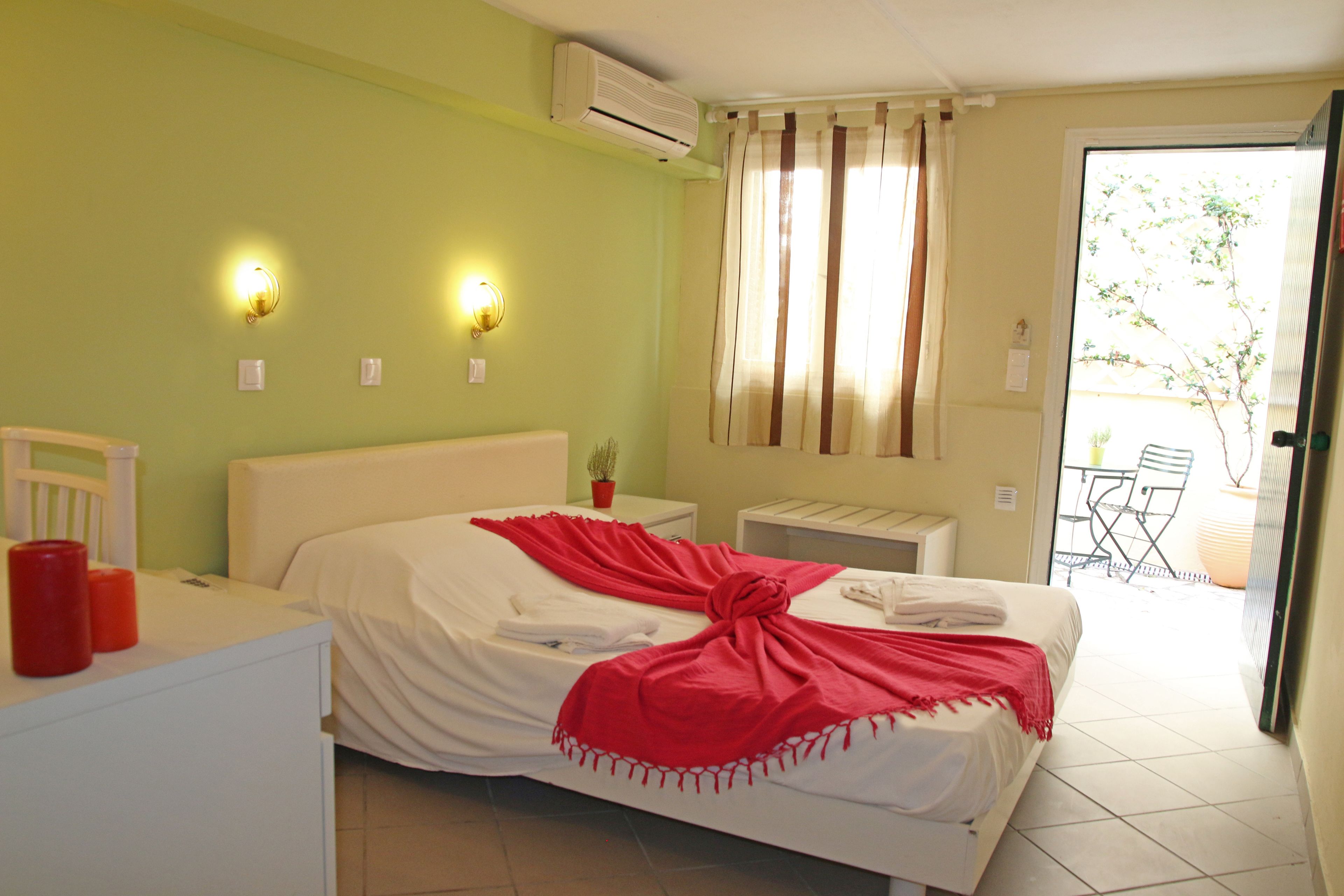 A hotel room with a bed, bedside table, and a small table with a potted plant.