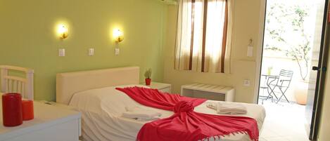 A hotel room with a bed, bedside table, and a small table with a potted plant.