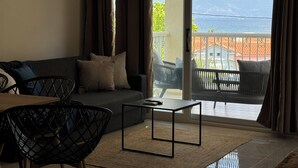 Un salón con sofá, mesa de centro y vistas al mar a través de un ventanal corredero.