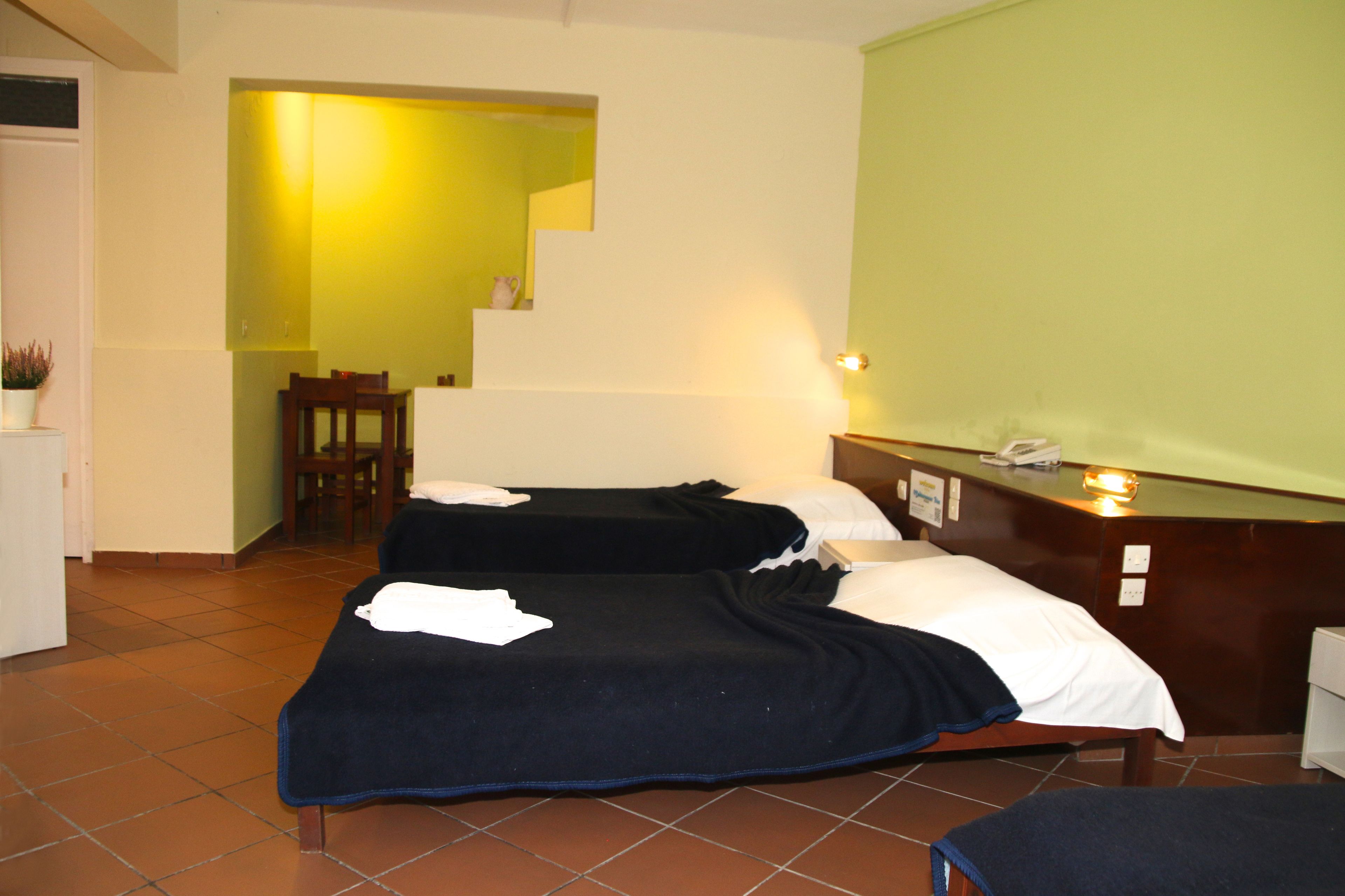 A hotel room with two beds, a desk, and a staircase leading to an upper level.