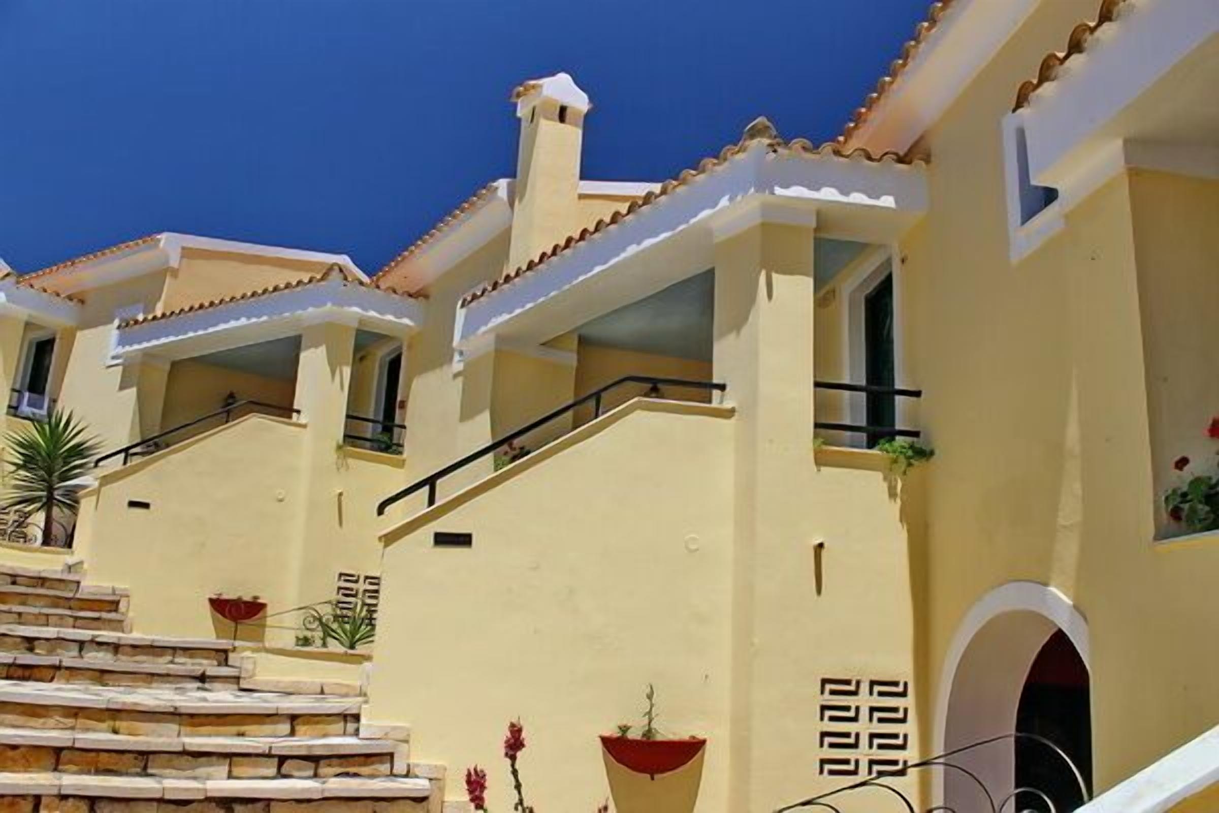 Un edificio con una escalera que conduce a un balcón, una chimenea y un pequeño ventanal de arco.