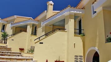 Un edificio con una escalera que conduce a un balcón, una chimenea y un pequeño ventanal de arco.