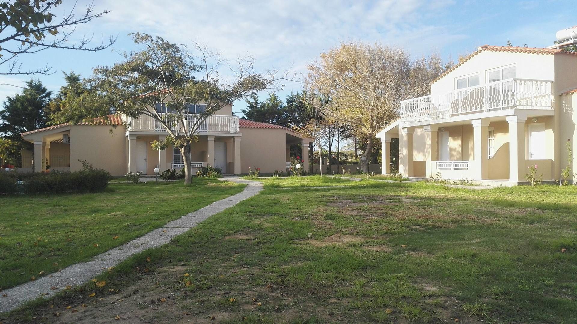 A residential area with two houses, a paved pathway, and a grassy lawn.