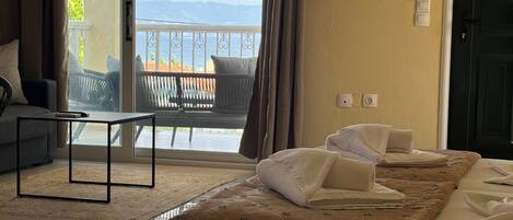 A hotel room with a bed, a sofa, a small table, and a view of the outdoors.