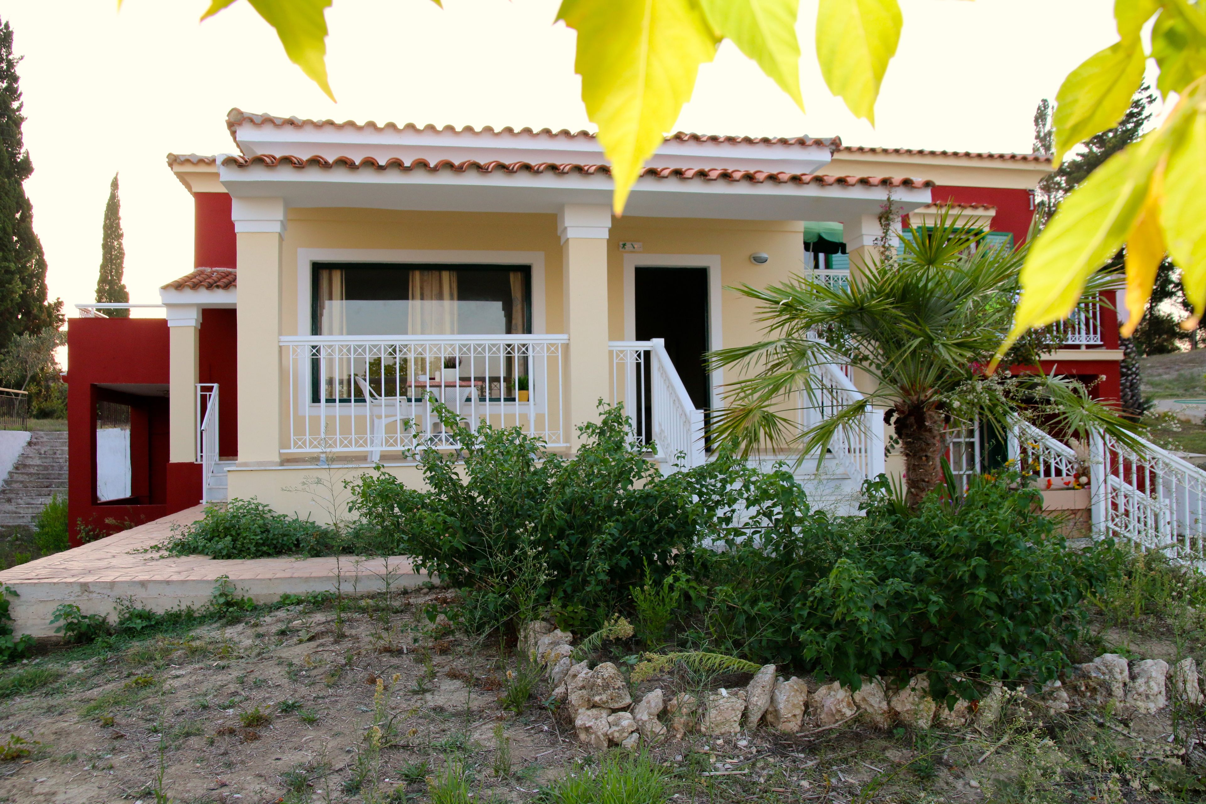Une maison à deux étages avec un balcon, un chemin en pierre et un palmier.