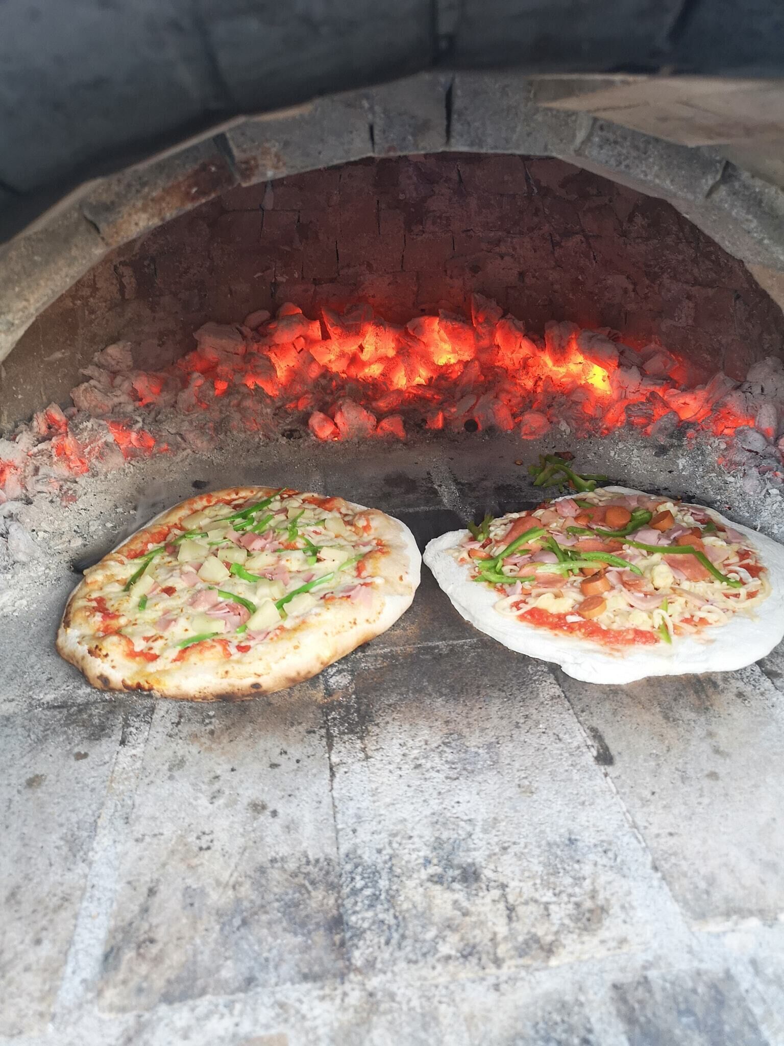 Twee pizza's worden in een bakstenen oven gebakken.