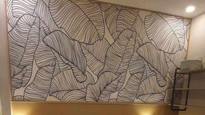 Camera d'albergo con un letto grande, due comodini con lampade, un muro decorato e una luce a soffitto.