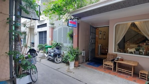 Una proprietà residenziale con cancello, una bicicletta, piante in vaso, una panchina di legno e una finestra con tende.