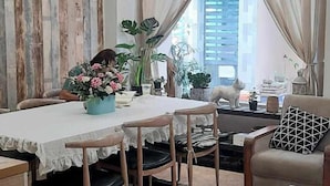Zona pranzo con tavolo apparecchiato per quattro persone, un lampadario e una ventola a soffitto.