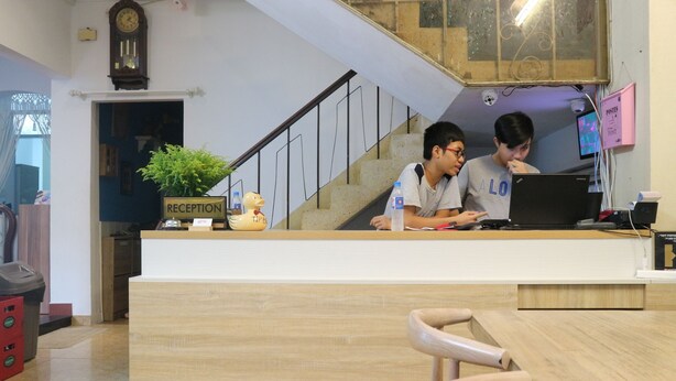 Una reception con due persone al lavoro, una scala e la segnaletica della reception.