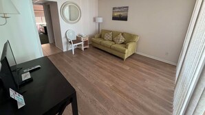 Una sala de estar con un sofá, una mesita, una lámpara y un ventilador de techo.